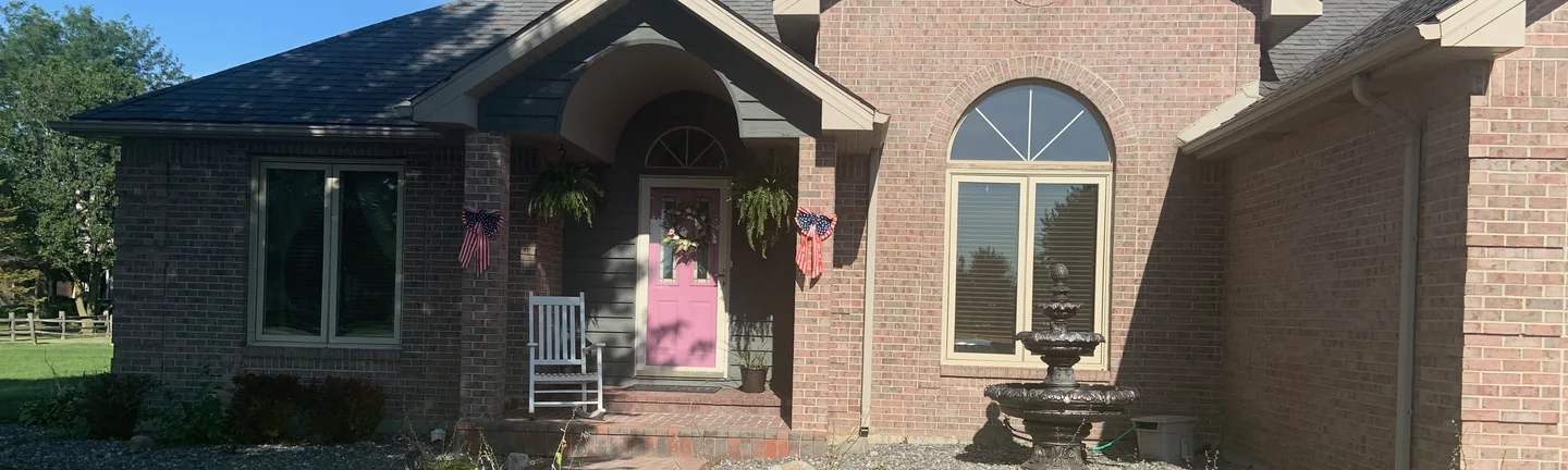 The front of the house in 2019, the entry set under a brick arch beside a tall arched window
