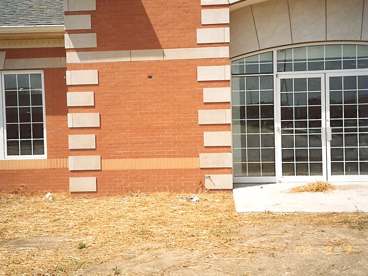 A wall of the business center in 2003, the course of upright brick at sill height reading a light orange against the cream limestone blocks beside it