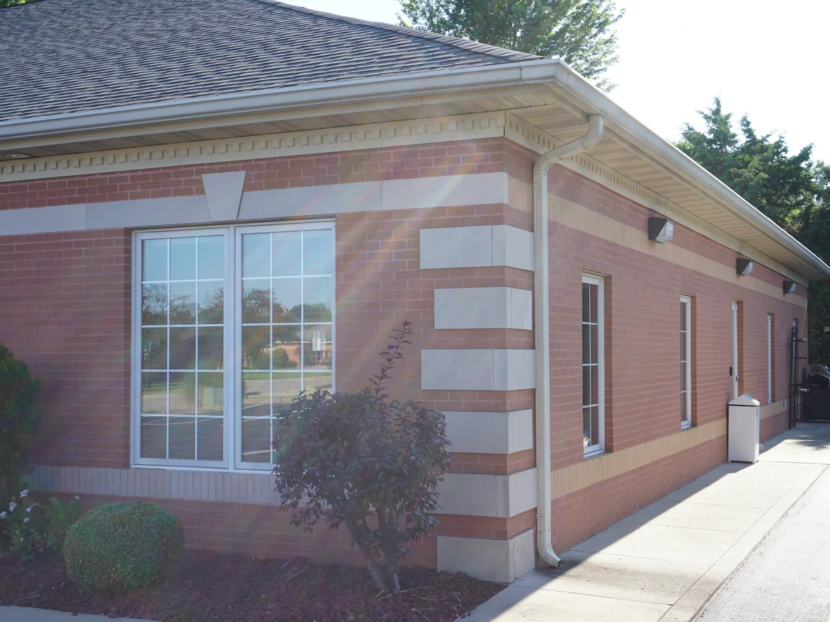 An outside corner in 2019 with stacked limestone quoins, the pale soldier course carrying around both faces into low sun