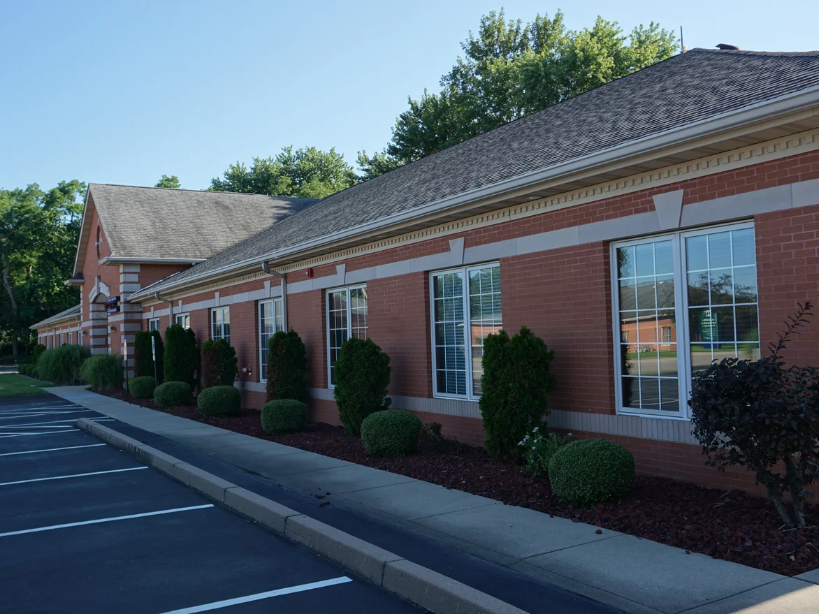 A row of windows along the parking lot side in 2019, the soldier course reading as one continuous pale band below the sills