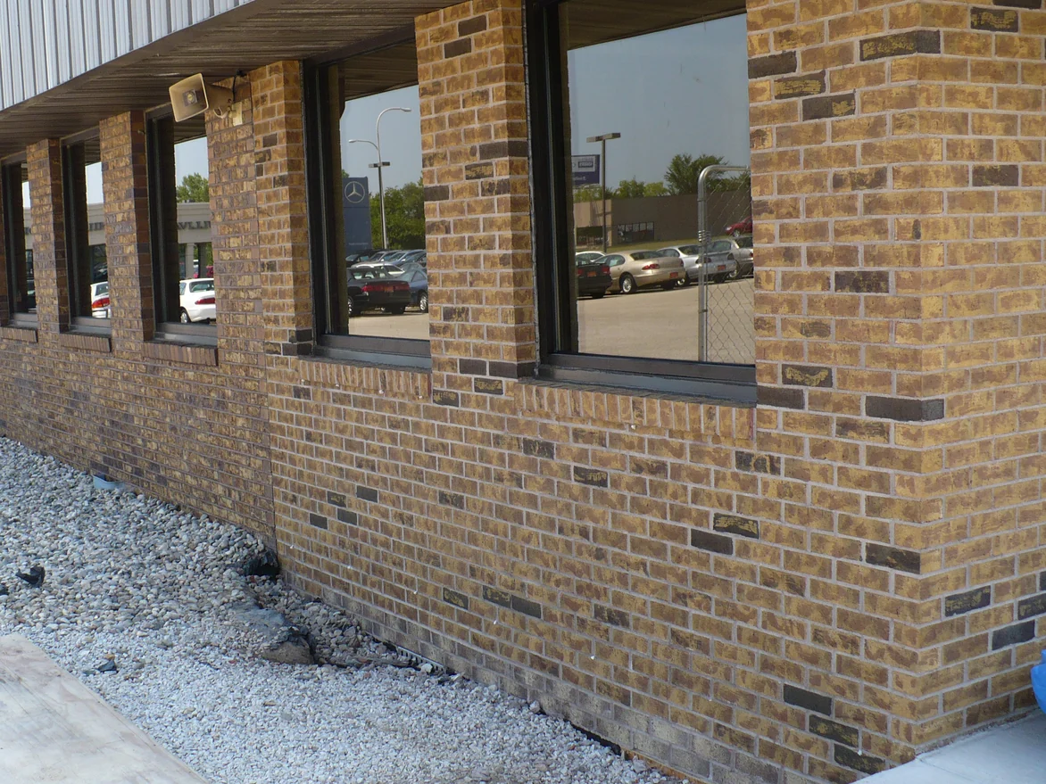 An outside corner of the dealership after the 2008 work, the brick on both faces reading as one tan and brown range with darker accent units scattered through it