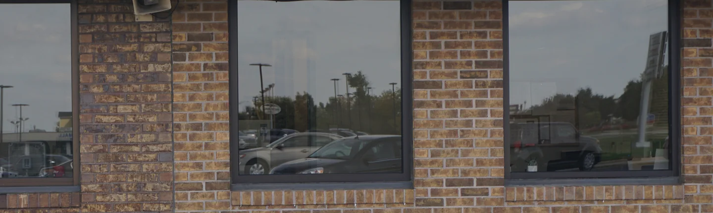 The dealership wall in 2019, its brick an even tan and brown range between dark window frames