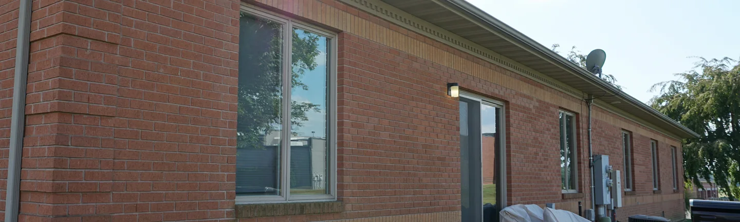 The long brick wall of the Illinois office in 2019, a buff soldier band running under the eaves and across the wall below the windows