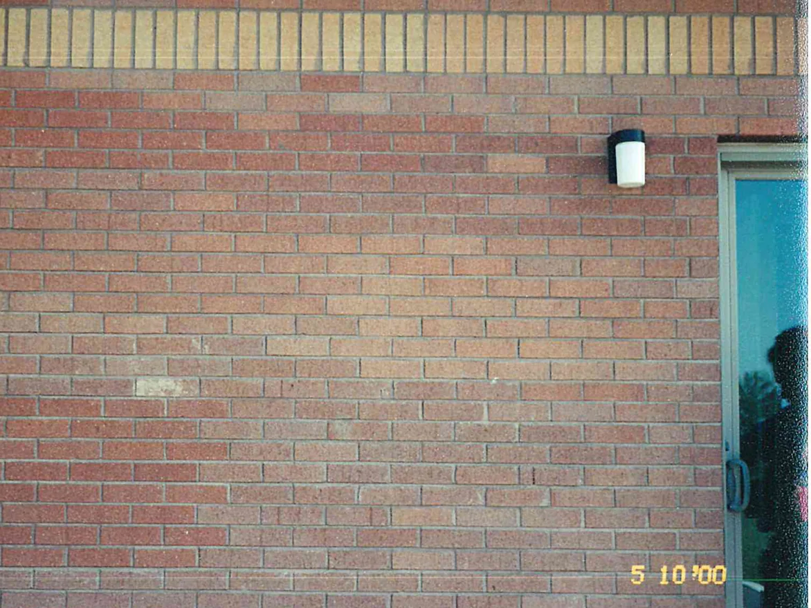 Close view of the wall in 2000 before the work, the field brick a patchy mix of pink, salmon and dull red with a course of upright buff units running across the top