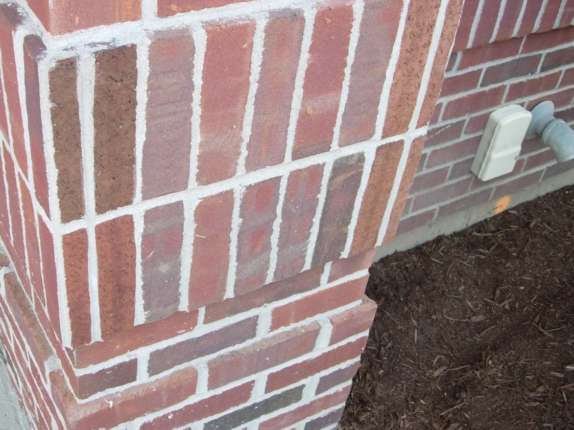A soldier course corner later in 2007, the upright units reading in the red brown range of the wall around them, a meter box and hose bib on the return wall