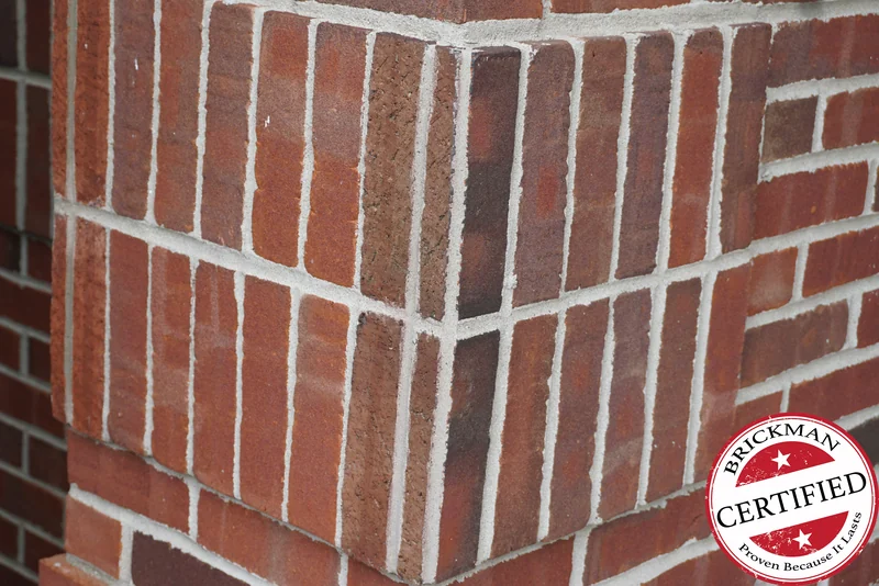 The soldier course corner in 2019, the upright units and the brick on both faces reading as one red brown range, foliage against the wall behind and the certification stamp at the corner of the frame