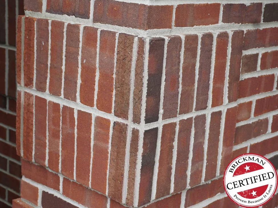 The soldier course corner in 2019, the upright units and the brick on both faces reading as one red brown range, with the certification stamp at the corner of the frame.