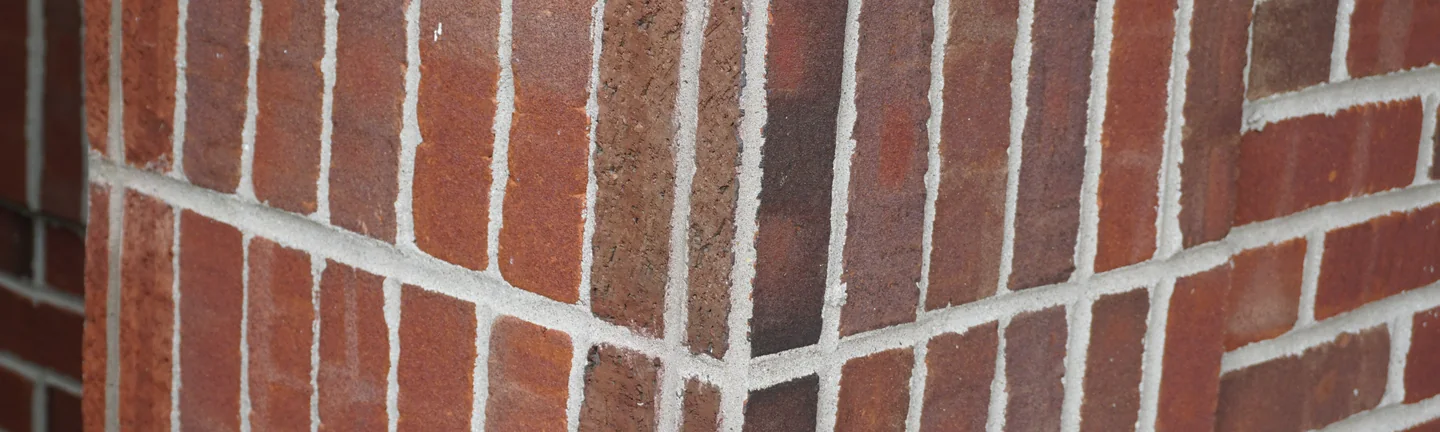 An outside corner of the Illinois building in 2019, the upright soldier course brick running down the corner in the same red brown range as the wall