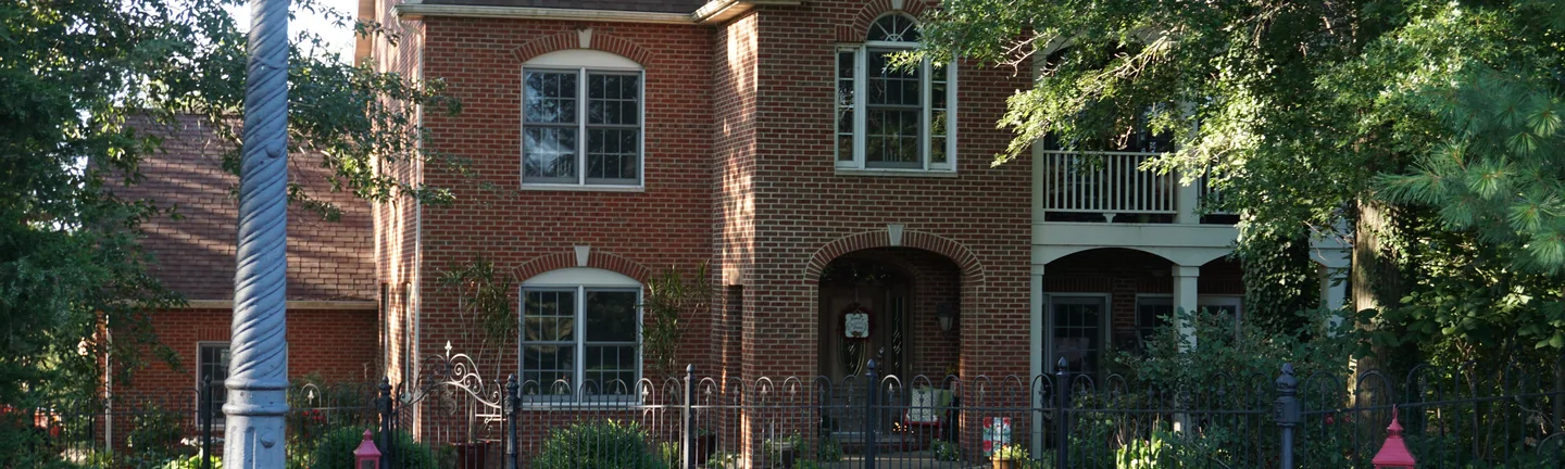 A two-story red brick house in 2019, its arched brick entry set between tall windows under a steep gable