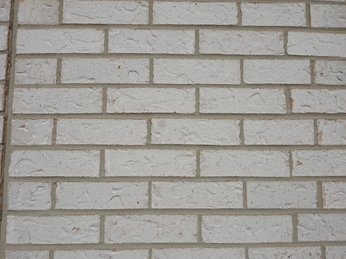 Close view of the white brick in 2019, each unit heavily textured and flecked with rust, the mortar joints a warm grey