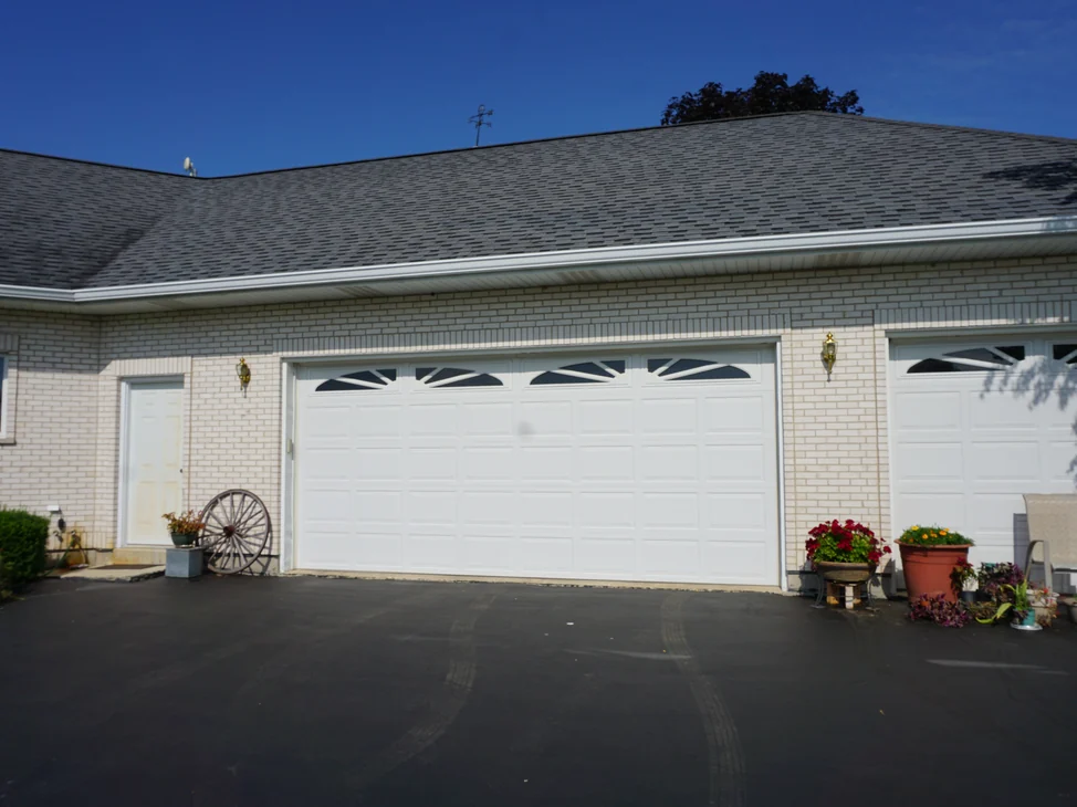 The garage end of a single-story white brick home in 2019, the brick one even color from the eaves down to the driveway