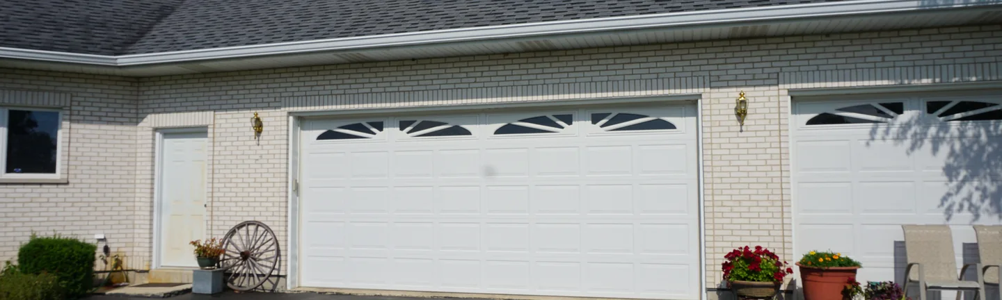 The garage end of a single-story white brick home in 2019, the brick reading as one even color across the wall