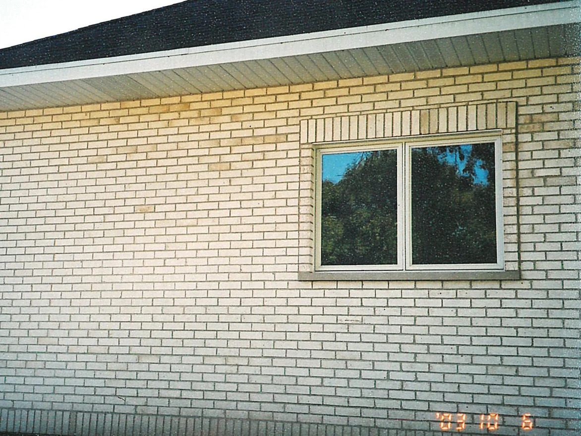 A side wall of the house in 2003, tan brick showing through the white in patches along the top courses under the eaves
