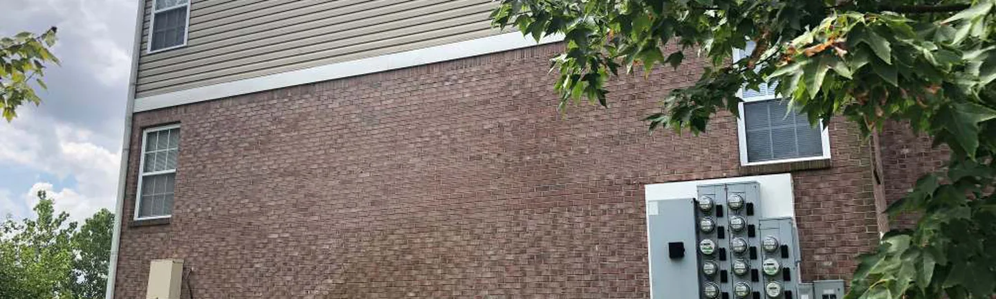The side elevation of the Indiana apartment building in 2019, red brown brick under tan siding