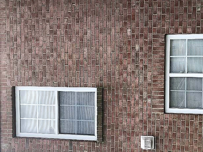 A window in the brick wall in 2019, the units around it in one red brown range with a small vent below