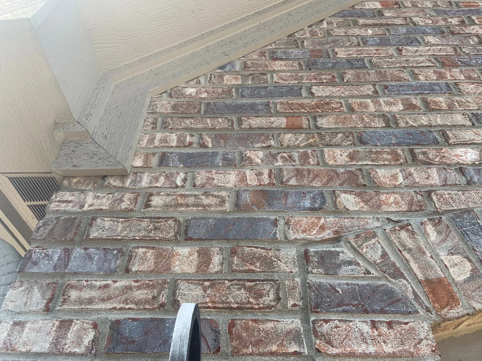 Brick running up to the gable soffit in 2019, seen at an angle, the blended units reading as one range against the trim