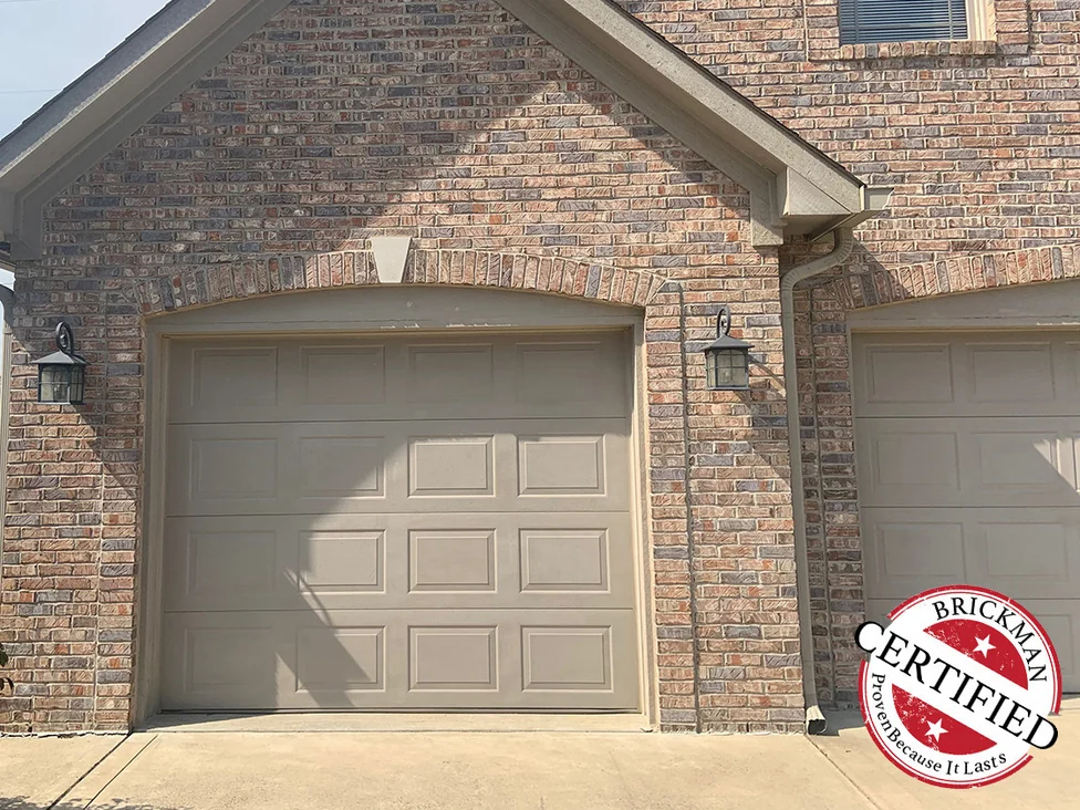 The gabled garage bay in 2019 with a brick arch over the door, the brick above and beside it reading as one blended range