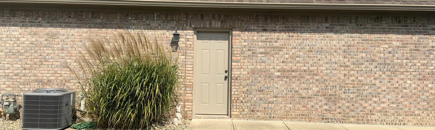 The side of the house in 2019, its blended brick reading as one tan and grey range under the eaves