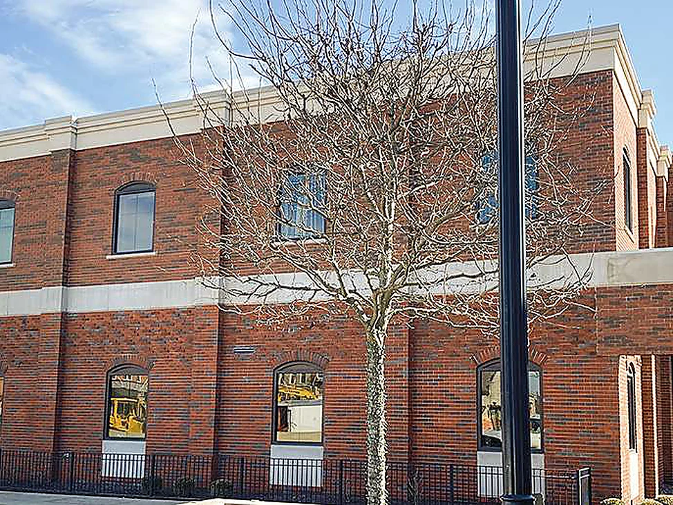 The bank in 2021, two stories of red brick with scattered dark headers carrying the length of the elevation to a canopied entrance at the far corner.