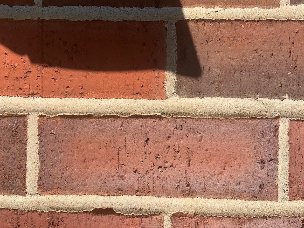 Three brick units filling the frame in 2019, their faces mottled red and brown with sand-textured mortar joints between them