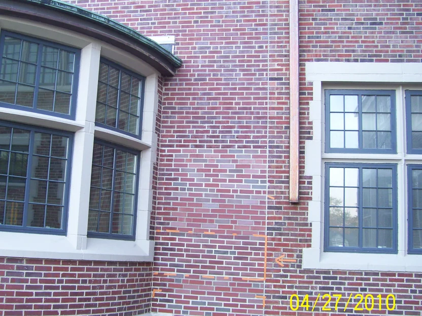 The same fill-in panel in April 2010 with its upper courses already darkened toward the original brick, and orange tape marking the lower courses still to be done