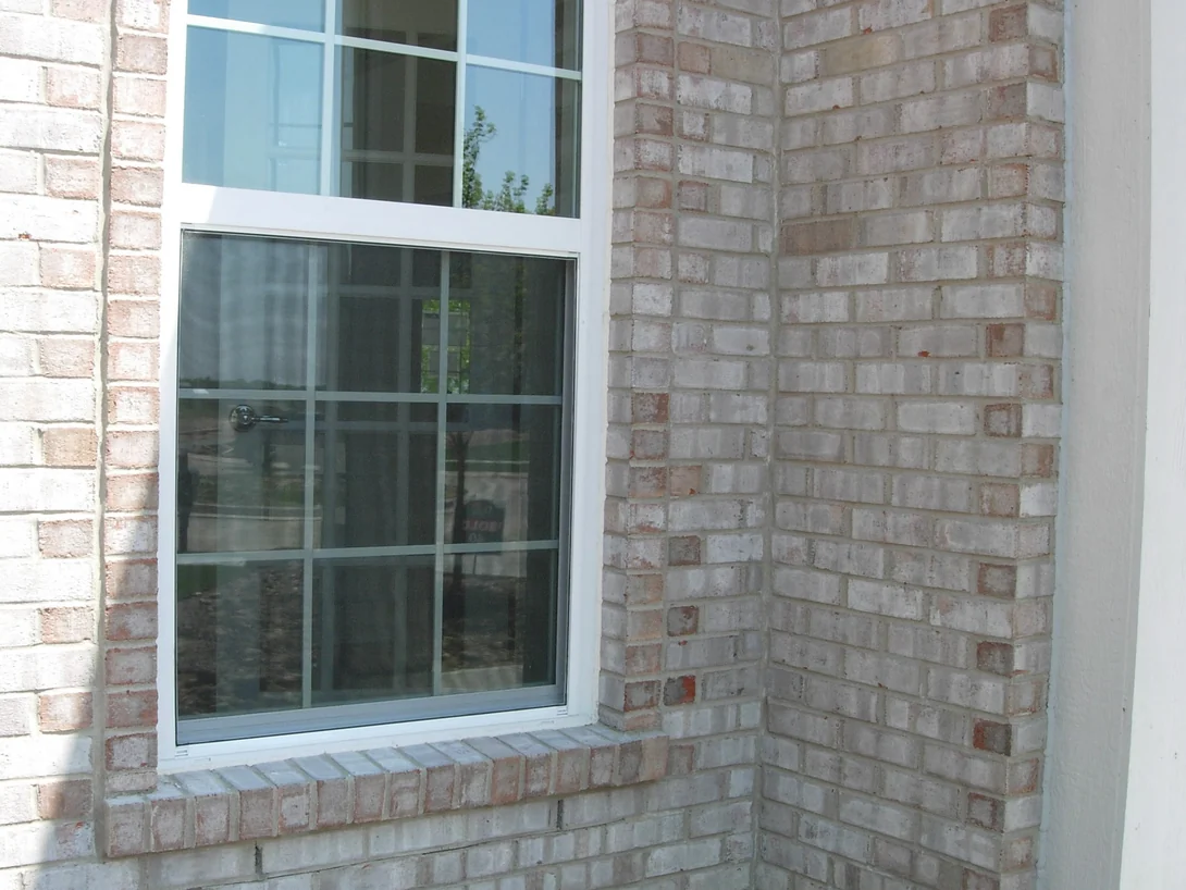 A ground floor window and the brick corner beside it in 2007, the wall a chalky cream and grey with bricks of clearly different tones scattered through it