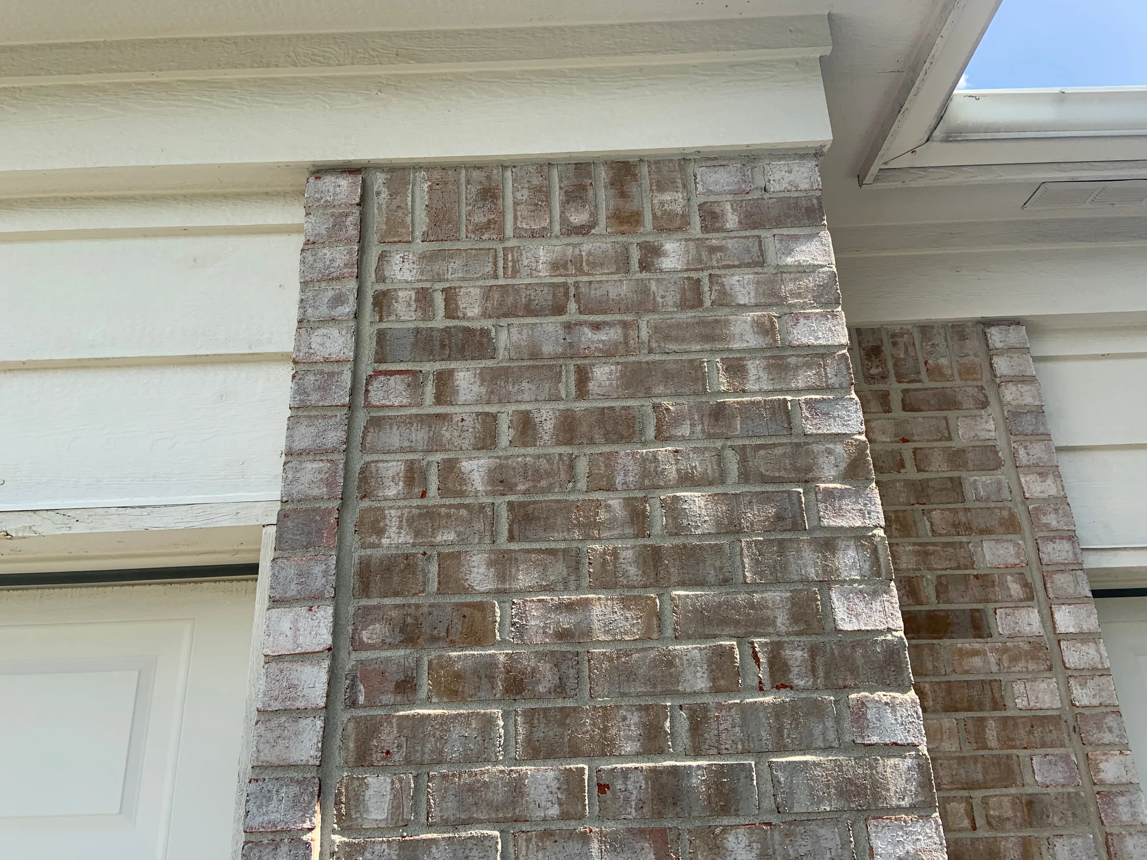 A brick pier under the soffit in 2019, seen close enough to read each unit, the tan and cream range holding across the face and around the return