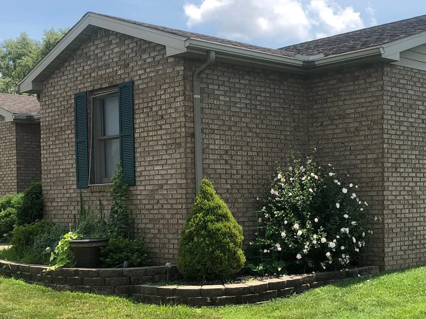 The gable wall around the shuttered window in 2019 at closer range, the brick reading as one even range from the eave to the planting bed