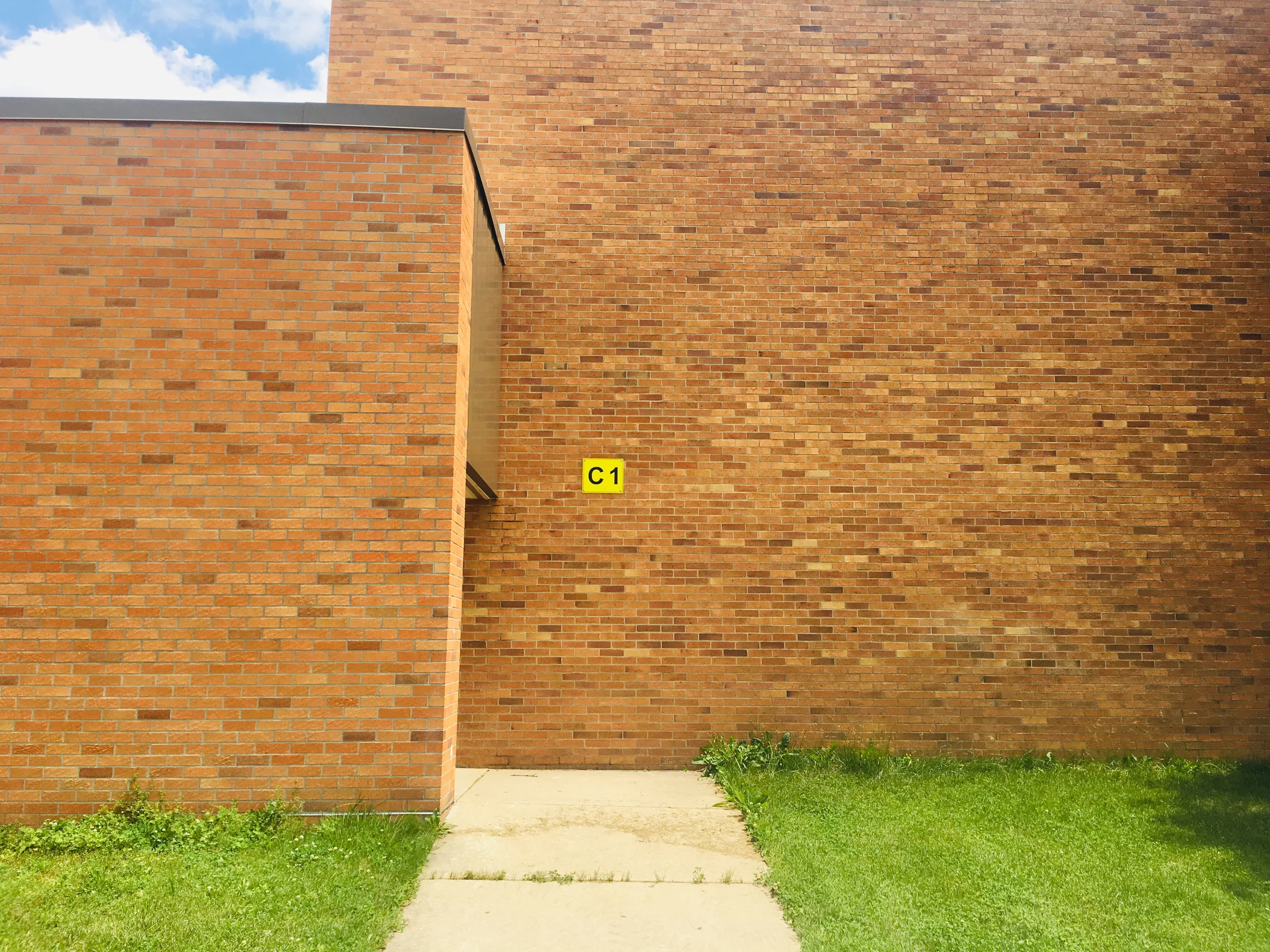Close view of the addition's brick in 2019, individual dark units reading at unit scale against the lighter units around them