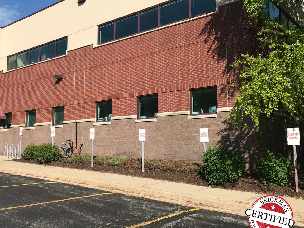 The same elevation in 2019 with reserved parking signs along the block base, the brick reading as one consistent red at distance