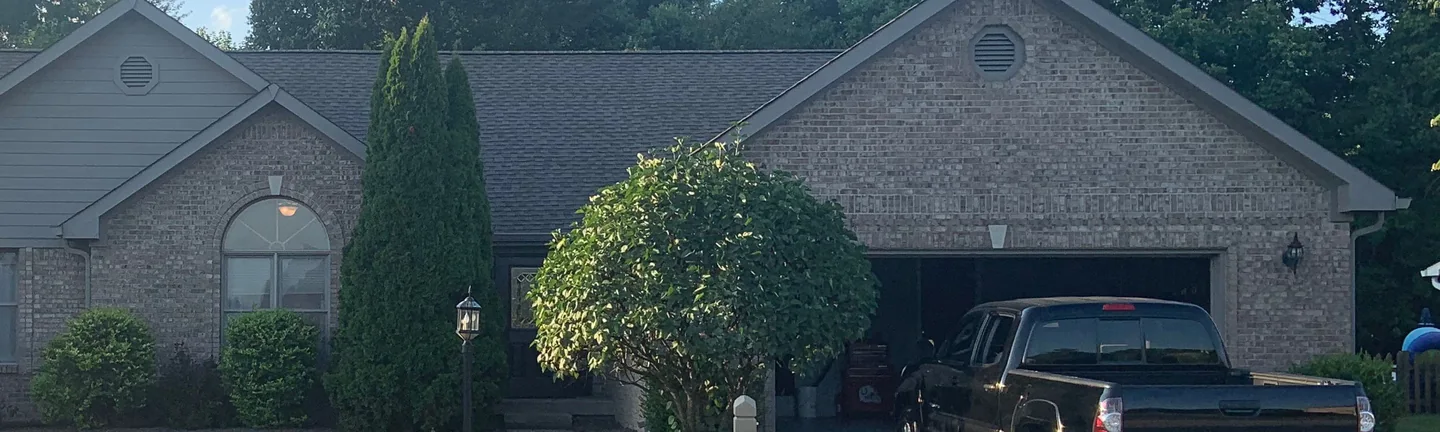 The front of the house in 2019, its brick one even light tan range across the entry gable and the garage wing