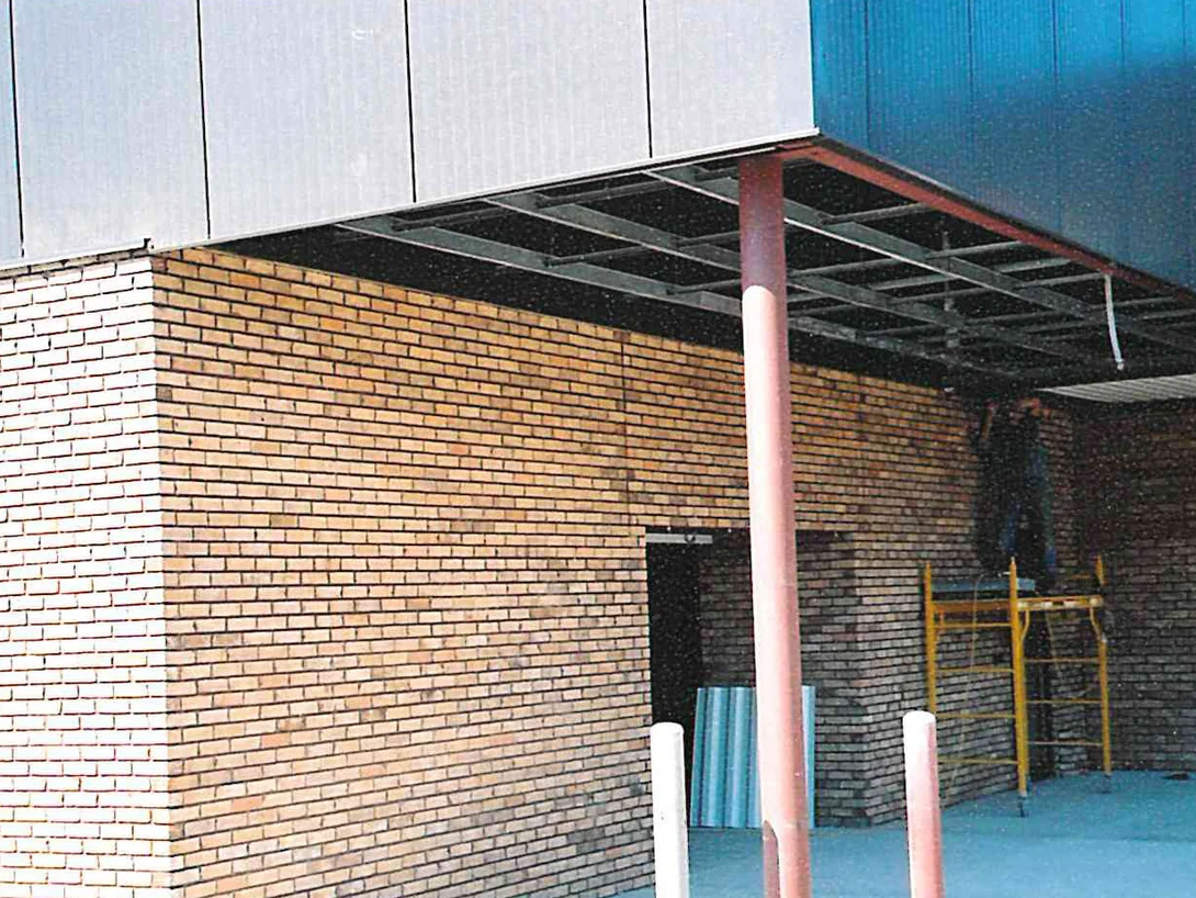 An outside corner of the showroom in 2003 beside a canopy still open to its steel framing, the brick a pale uneven tan and cream