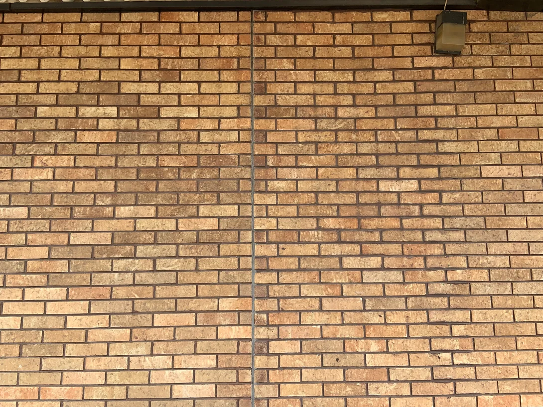 Close view of the stained brick at unit scale in 2019, the units ranging from cream through tan to orange brown across dark mortar