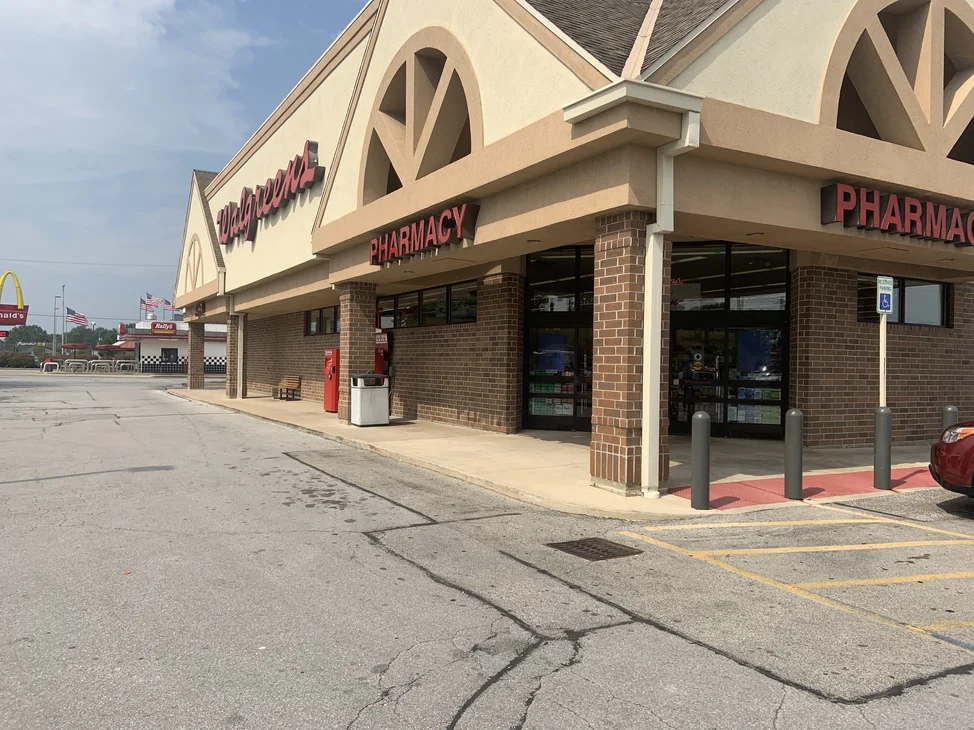 The store seen from across its car park in 2019, the brick along the whole front reading as one even red brown range under the pharmacy signs.
