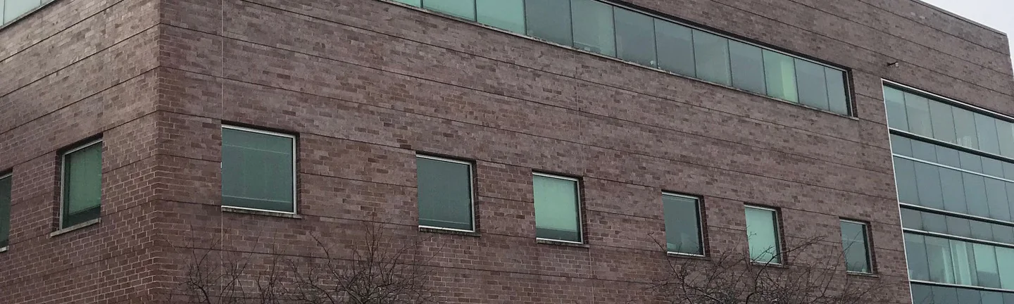 A wide band of the school's brick elevation in 2021, one even red range running past two rows of windows to a glazed bay