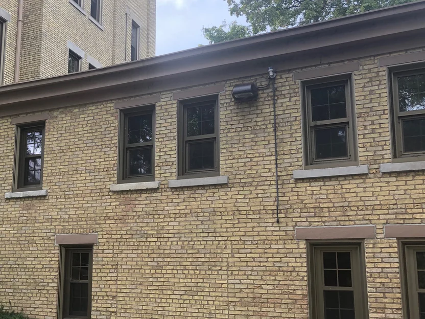 The same addition wall in 2019, one even buff range from the planting bed up past both rows of windows to the gutter, the main building beyond it at the left