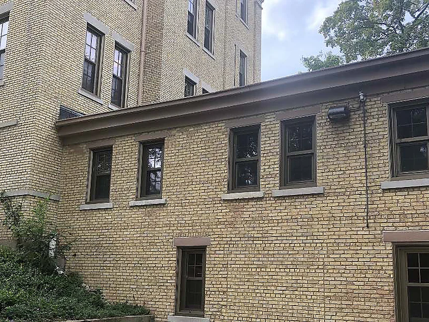 The courtyard in 2019, the two-storey addition on the right and the taller main building on the left, both walls holding the same buff brick range where they meet