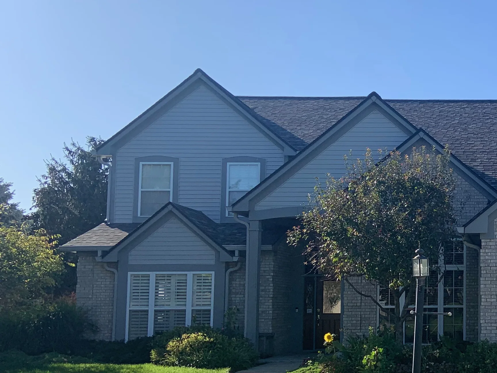The front of the house from the street in 2019, the brick below the siding reading as one even cream and grey range