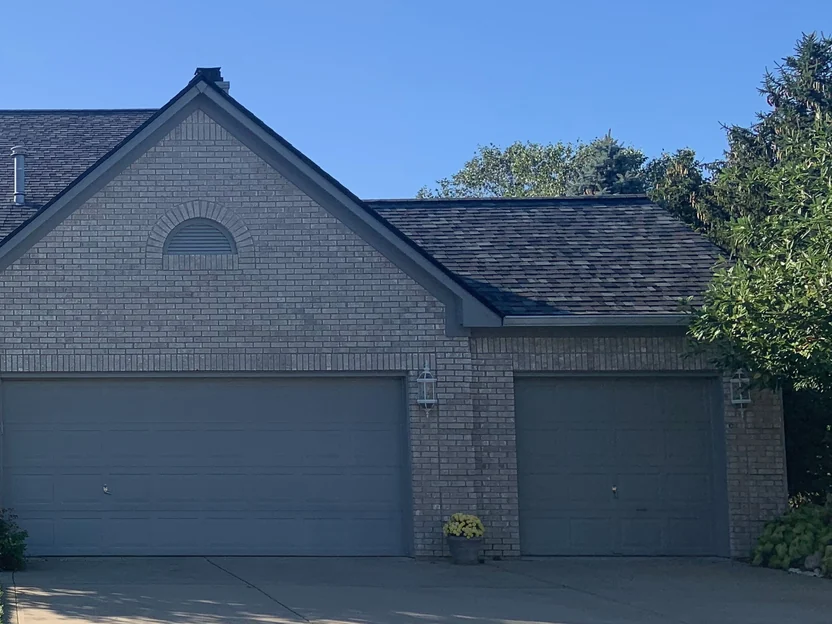 The garage wing in 2019, its brick gable and the arched vent above the doors in one consistent cream and grey blend