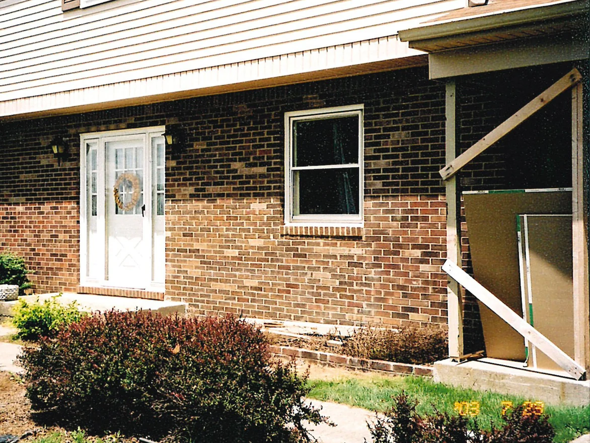The front door and the same window three days later in 2003, pale tan units now running through the brick to the right of the door and under the sill