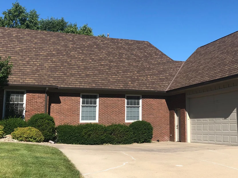 The house from further down the driveway in 2019, the long brick wall with two windows and trimmed shrubs running into the garage wing on the right