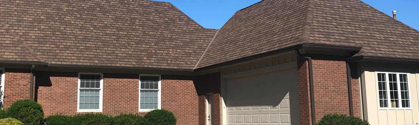The front of the Iowa house in 2019, red brick running from the main house across the garage wing under one brown roof
