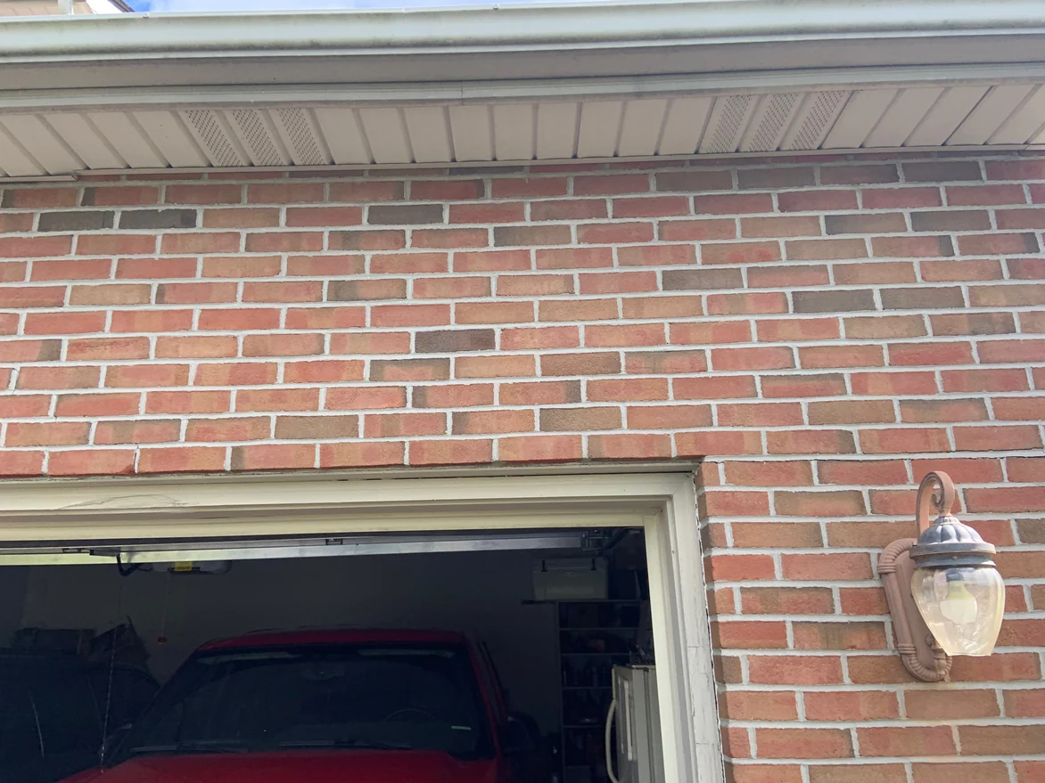 Close view of the brick above the garage opening in 2019, individual units running from pink through tan to dark brown with no pale run standing out of the wall