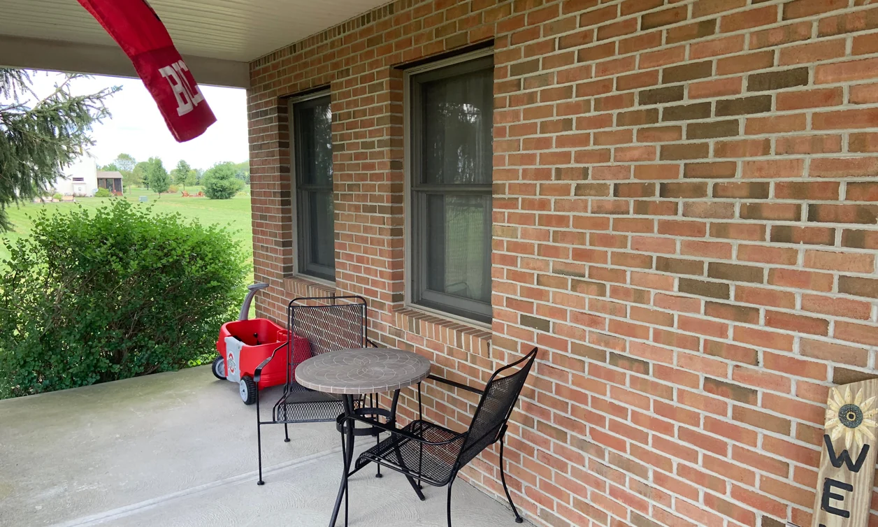 The front porch of a Johnstown, Ohio home in 2019, its red brick an even blend twenty years after the pale run was darkened
