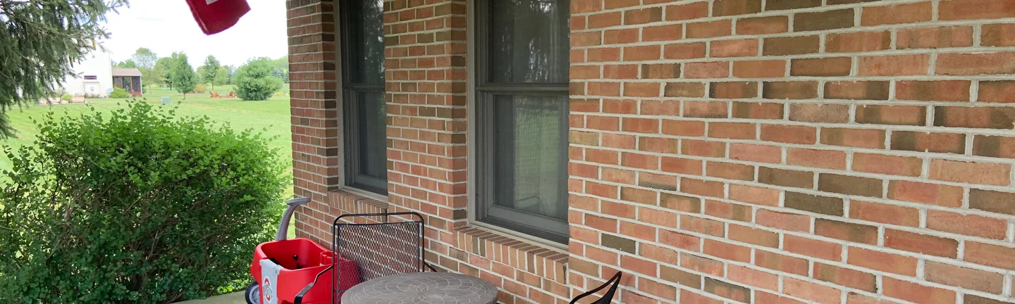 The covered porch of the Johnstown house in 2019, its brick an even red and tan range beside two sash windows