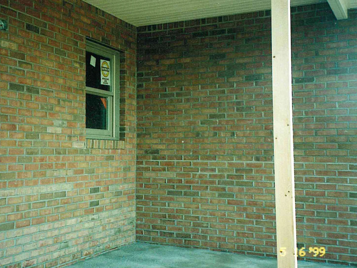 The inside corner of the covered porch in 1999, two brick walls meeting under a white soffit, whole courses reading pale against the darker units around them