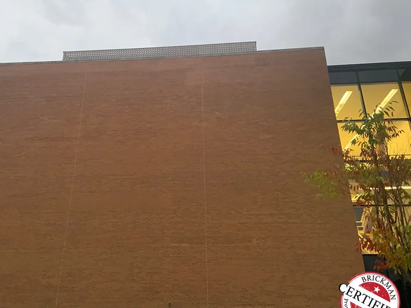 The full end wall in 2019, one even brown across every course, with the certification stamp in the corner and the lit glass bay at the right