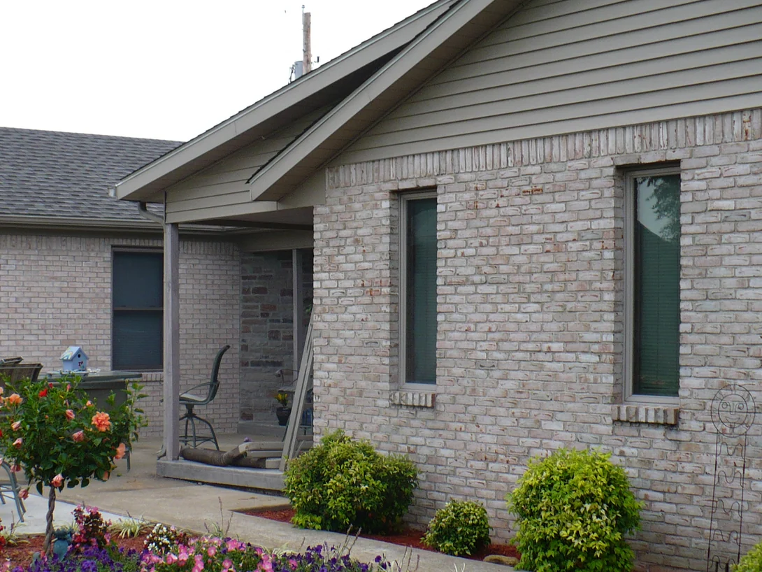 The same patio in 2008 after staining, seen from further right, the wall on the left now a pale grey white close to the gable wing beside it, with shrubs and a fresh bed of red mulch along the base