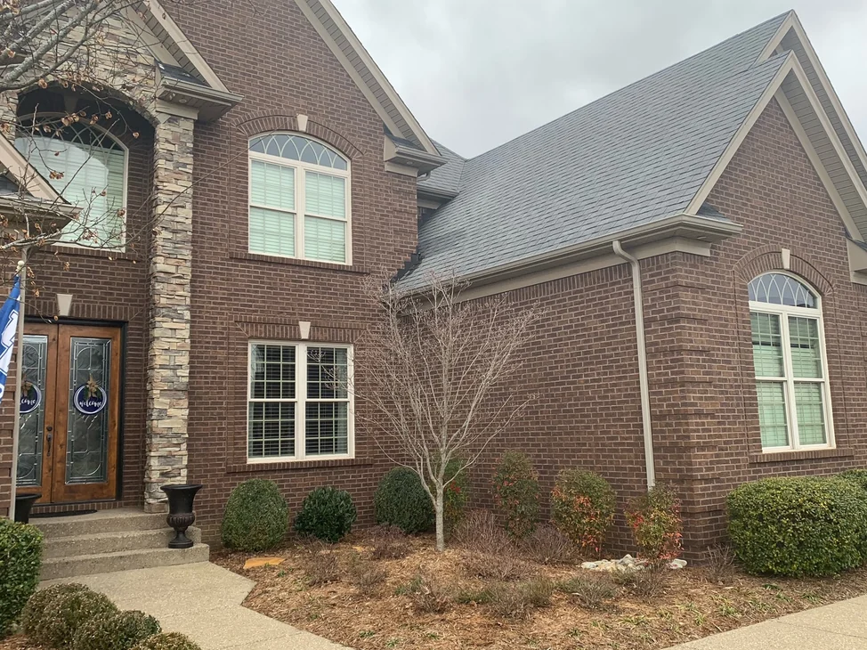 The front of the Kentucky house in 2019, dark brick and dark mortar running from the stone entry column past the front door to a side elevation
