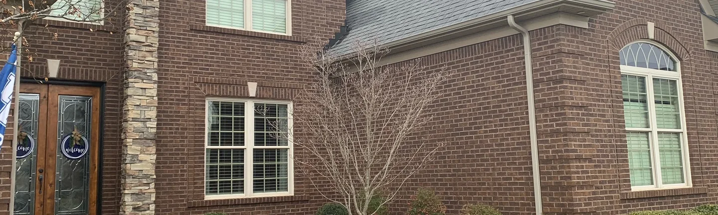 The front of the Kentucky house in 2019, dark brown brick with dark mortar joints beside a stone entry column